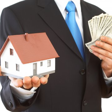 man in suit holding money and miniature house debt consolidation